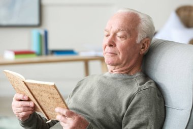 Evde kitap okuyan yaşlı adamın portresi