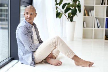 Yakışıklı Afro-Amerikalı adam evde pencere yakınında oturan