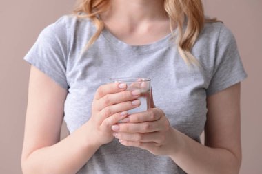 Renkli arka planda bir bardak temiz su olan kadın, yakın plan.