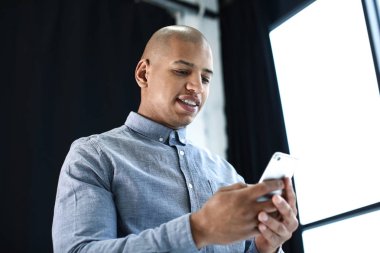 Ofisinde cep telefonu olan Afro-Amerikalı bir adam.