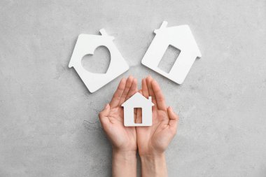 Gri arka plan üzerinde evlerin figürleri ile Kadın elleri