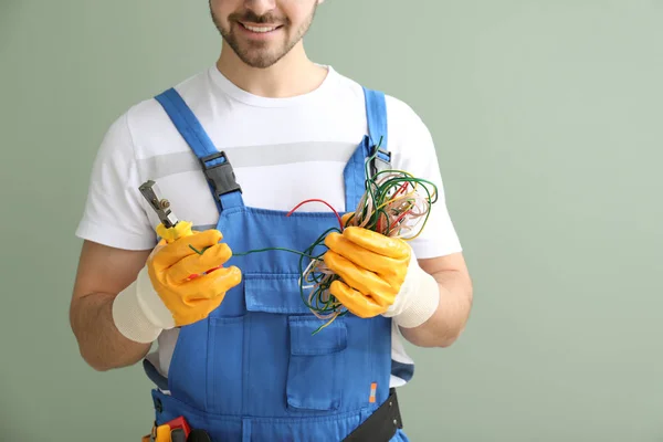 Manlig elektriker med trådar och verktyg på färg bakgrund, närbild — Stockfoto