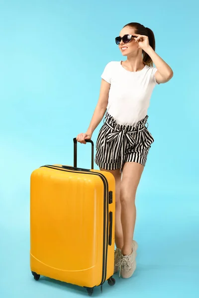 Female traveler with suitcase on color background — Stock Photo, Image