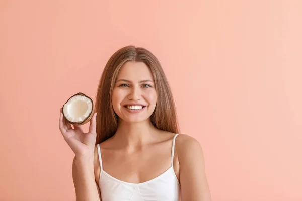Beautiful young woman with coconut on color background — Stock Photo, Image