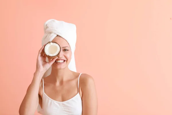 Beautiful young woman with coconut on color background — Stock Photo, Image