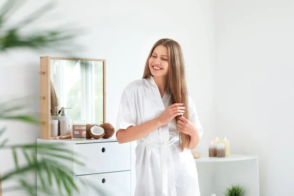 Mooie jonge vrouw die kokosolie op haar thuis aanbrengt — Stockfoto