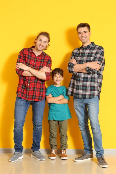 Happy gay couple with adopted child near color wall — Stock Photo, Image
