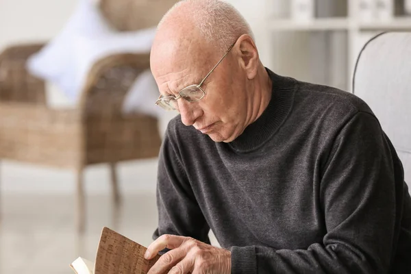 Portret van oudere man lezen boek thuis — Stockfoto