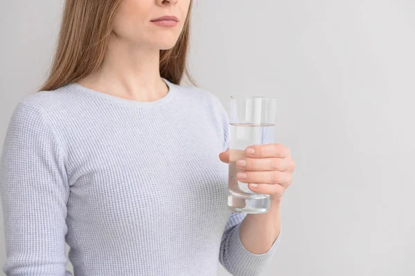 Γυναίκα με ένα ποτήρι φρέσκο νερό στο φως φόντο — Φωτογραφία Αρχείου