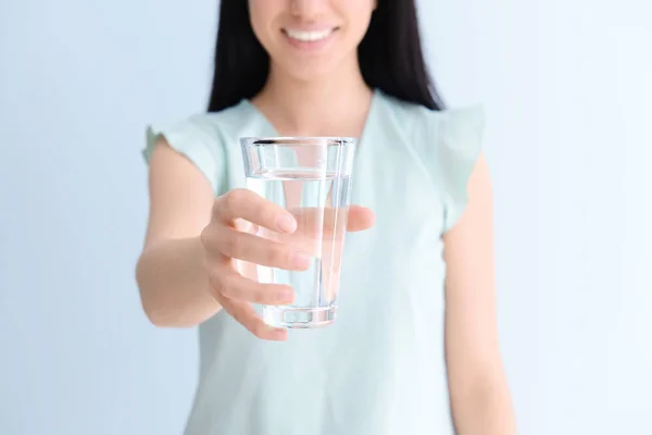 光の背景に淡水のガラスを持つ女性 — ストック写真