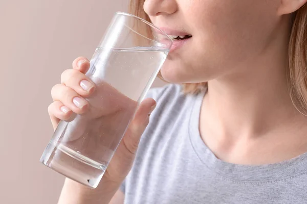 Woman drinking fresh water on color background, closeup — Stock Photo, Image