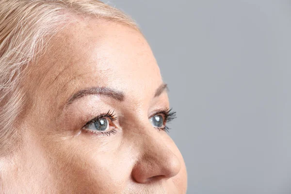 Mature woman on light background, closeup — Stock Photo, Image