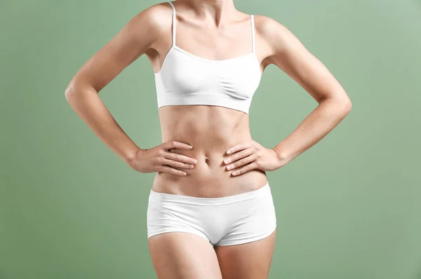 Hermosa mujer joven en ropa interior sobre fondo de color. Concepto de cirugía plástica — Foto de Stock