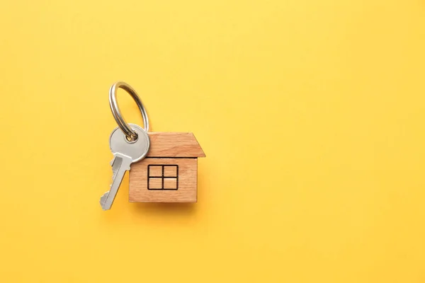 Key with trinket in shape of house on color background — Stock Photo, Image