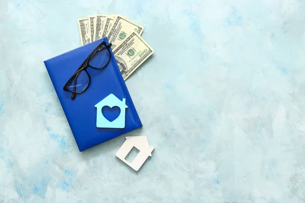 Notebook, figures of houses, glasses and money on table — Stock Photo, Image