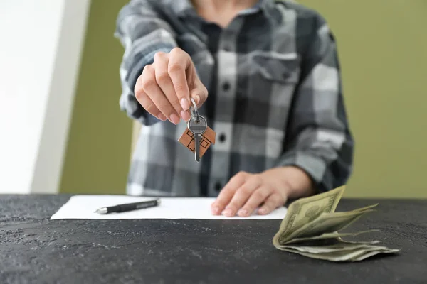 Real estate agent with money and key at table