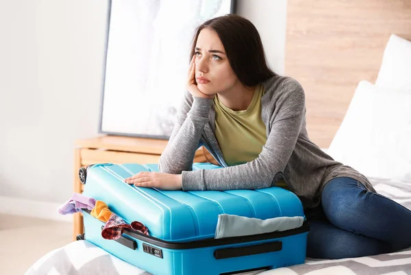 Triste joven mujer haciendo las maletas en casa. Concepto de viaje —  Fotos de Stock