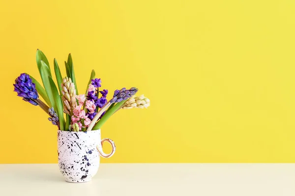 Beautiful hyacinth flowers in cup on table against color background — Stock Photo, Image