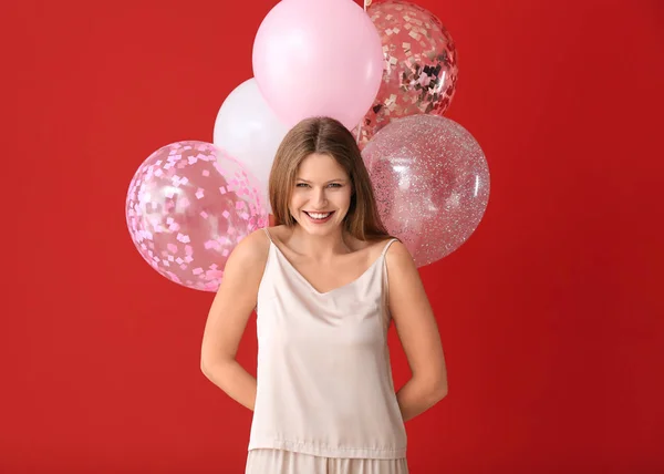 パジャマと色の背景に気球を持つ美しい若い女性 — ストック写真
