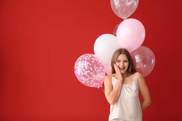 Mulher bonita em pijama e com balões de ar no fundo de cor — Fotografia de Stock