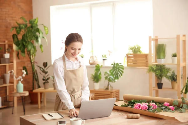 Jonge bloemist werken met laptop in de winkel — Stockfoto