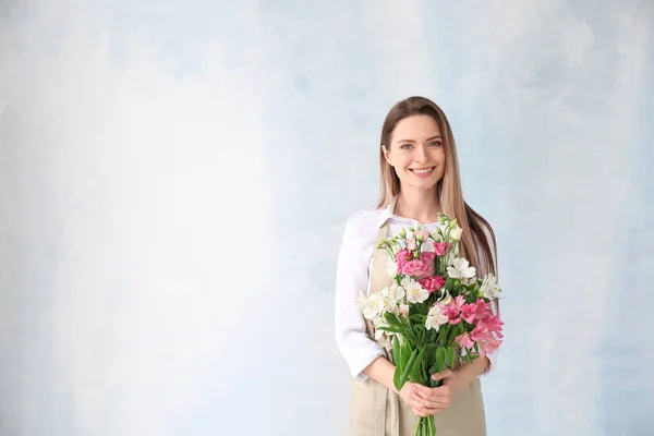 Young female florist with bouquet on color background — Stock Photo, Image