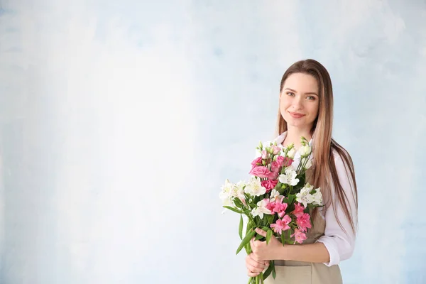 Young female florist with bouquet on color background — Stock Photo, Image