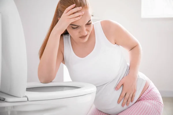 Молодая беременная женщина, страдающая токсикозом в туалете — стоковое фото