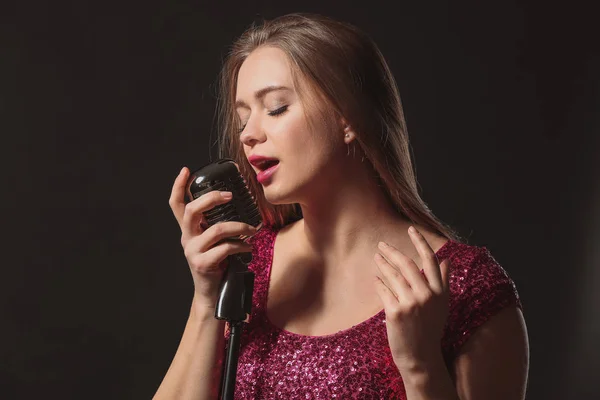 Hermosa cantante femenina con micrófono sobre fondo oscuro —  Fotos de Stock