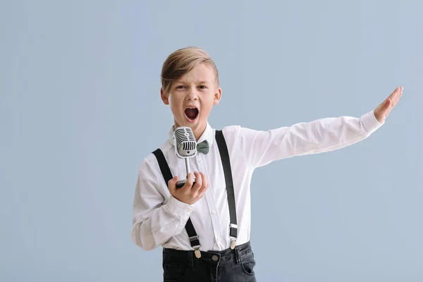 Lindo niño con micrófono cantando contra el fondo de color — Foto de Stock