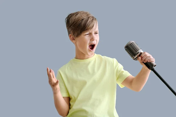 Carino bambino con il microfono che canta contro lo sfondo di colore — Foto Stock