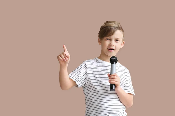 Menino bonito com microfone cantando contra fundo de cor — Fotografia de Stock