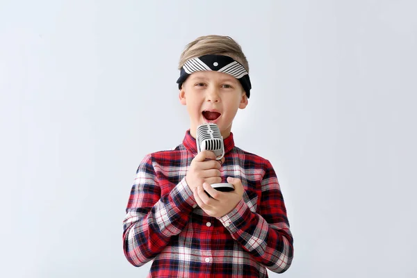 Menino bonito com microfone cantando contra fundo claro — Fotografia de Stock