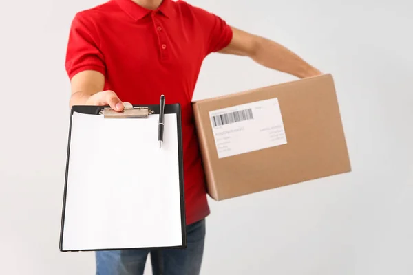 Delivery man with box and clipboard on white background — Stock Photo, Image