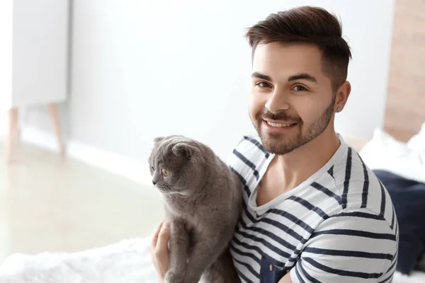 Young man with cute funny cat at home — Stock Photo, Image