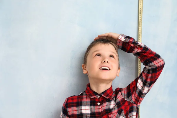 Lindo niño midiendo altura cerca de la pared de color — Foto de Stock