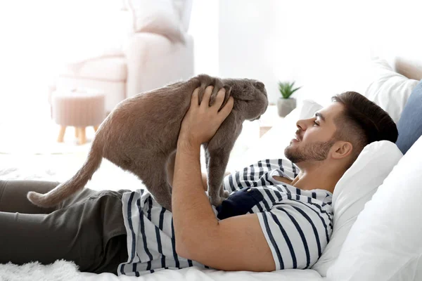 Young man with cute funny cat at home — Stock Photo, Image