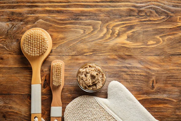 Brushes and body scrub on wooden background — Stock Photo, Image