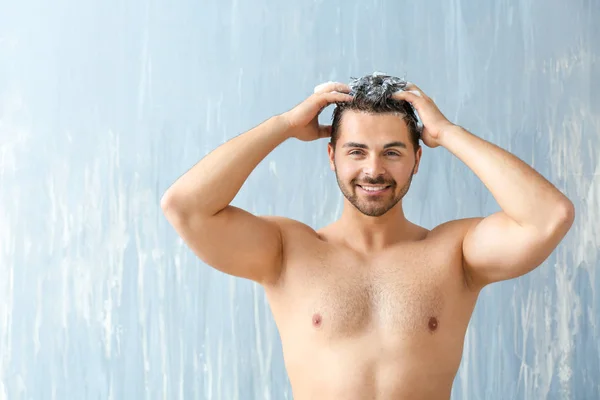 Handsome man washing hair on grey background — Stock Photo, Image