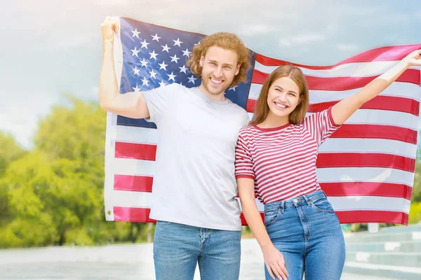 Feliz pareja joven con bandera de EE.UU. al aire libre. Fiesta del Día de la Independencia — Foto de Stock
