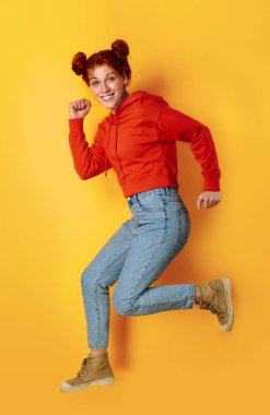 Renkli arka planda güzel atlama Redhead kadın