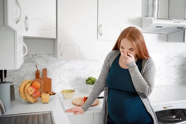 Молода вагітна жінка, що страждає токсикозом на кухні — стокове фото