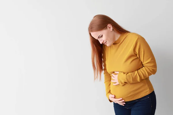 Young pregnant woman feeling bad on light background — Stock Photo, Image