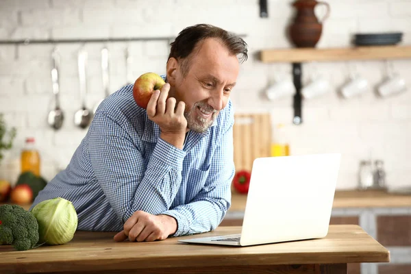 Bello uomo maturo con computer portatile in cucina — Foto Stock
