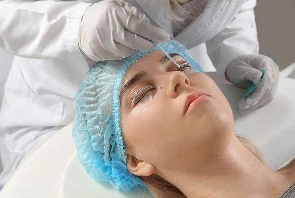 Young woman undergoing procedure of eyelashes lamination in beauty salon — Stock Photo, Image