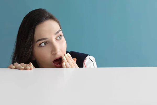 Surprised young woman near table on grey background