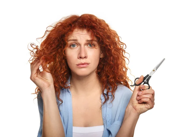 Mulher bonita descontente com seu cabelo segurando tesoura no fundo de cor — Fotografia de Stock