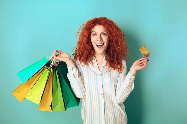 Krásná žena s nákupními taškami a kreditní kartou na barevném pozadí — Stock fotografie