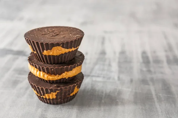 Tasty chocolate peanut butter cups on grey table