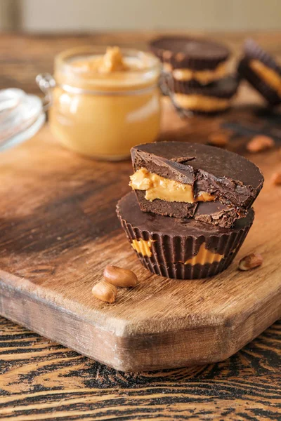 Tasty chocolate peanut butter cups on wooden board